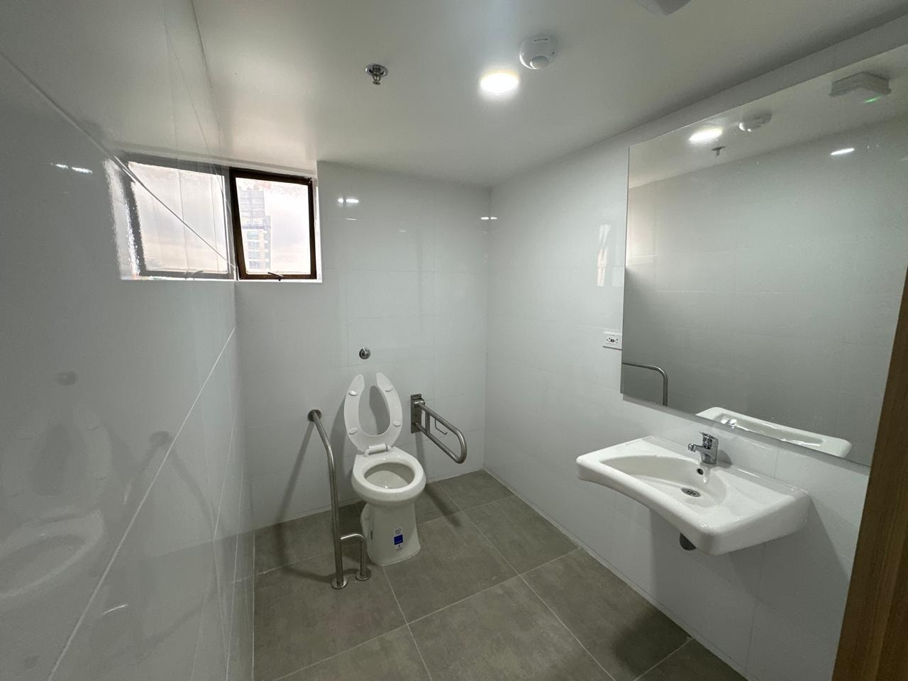 Mostrador de recepción con pared de acento teal, ventanas amplias y piso en madera