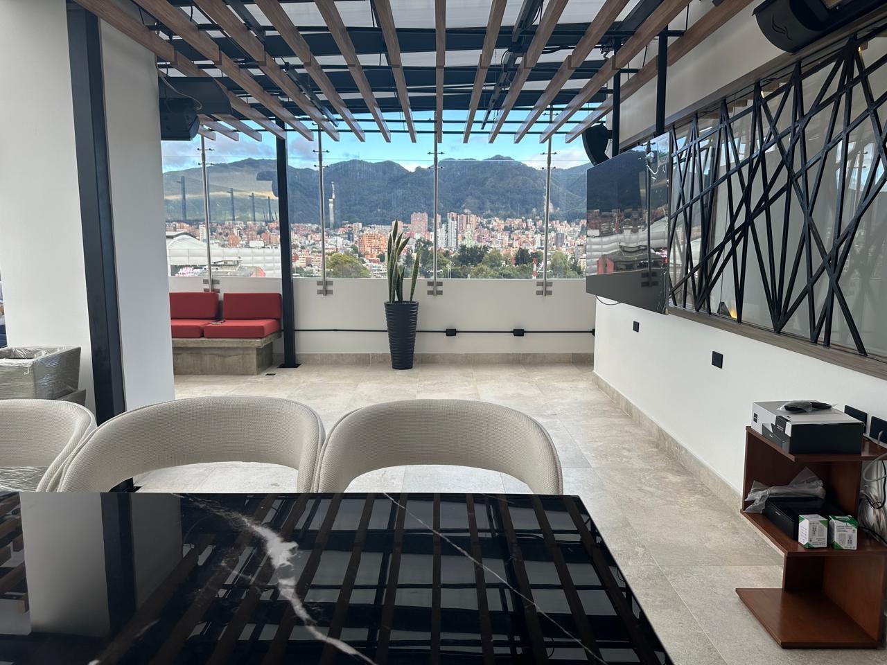 Comedor con sillas beige, mesa en mármol negro y vista panorámica a los cerros de Bogotá