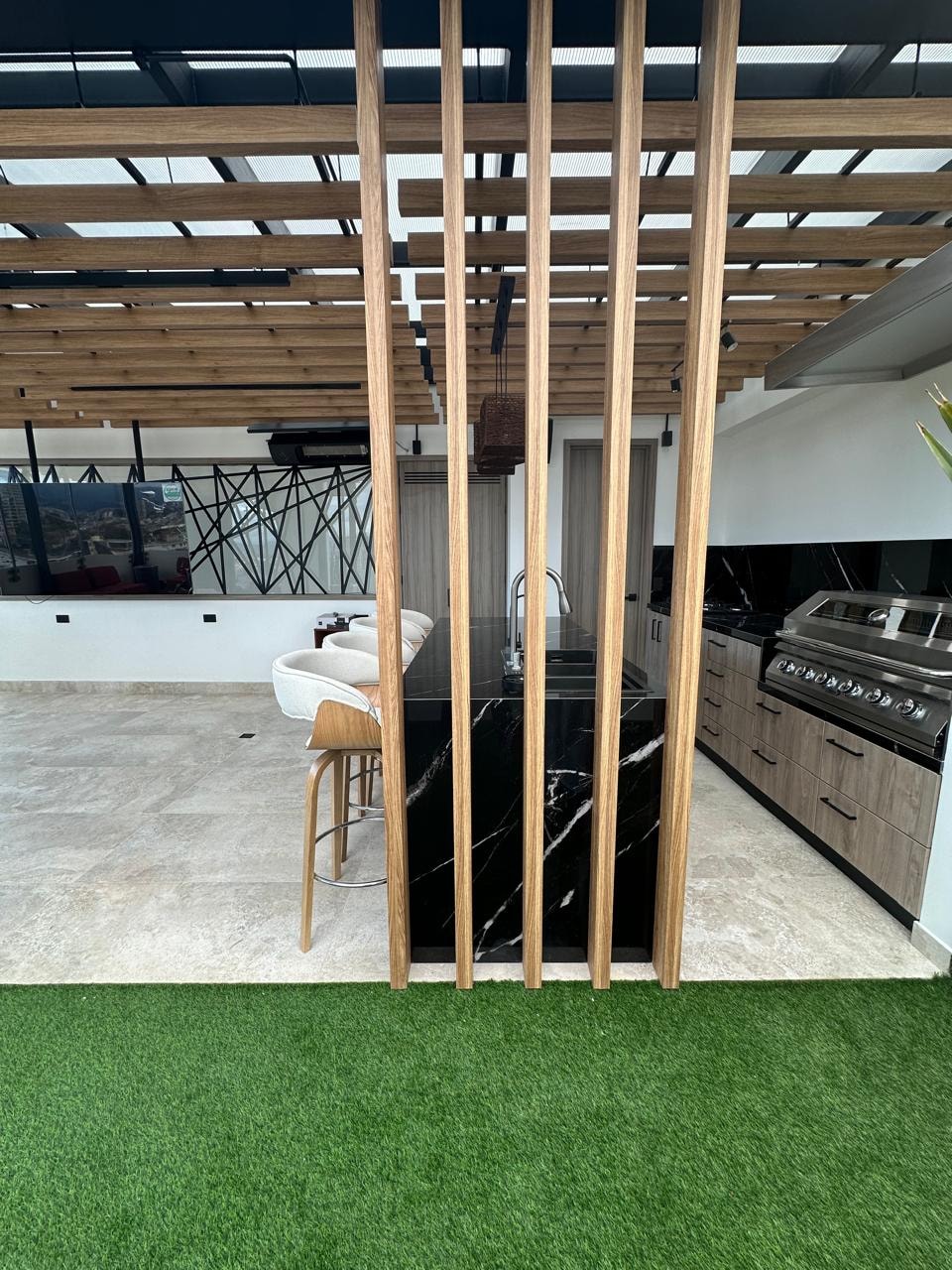 Vista general de la terraza con divisor de madera, zona de grama sintética y cocina al fondo